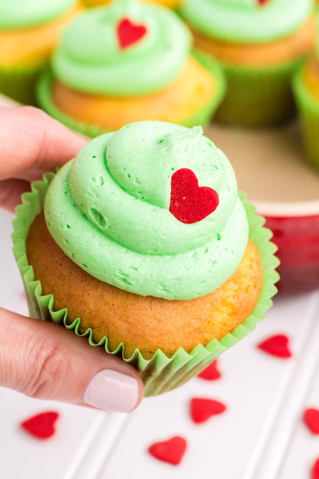 woman's hand holding adorable grinch cupcake