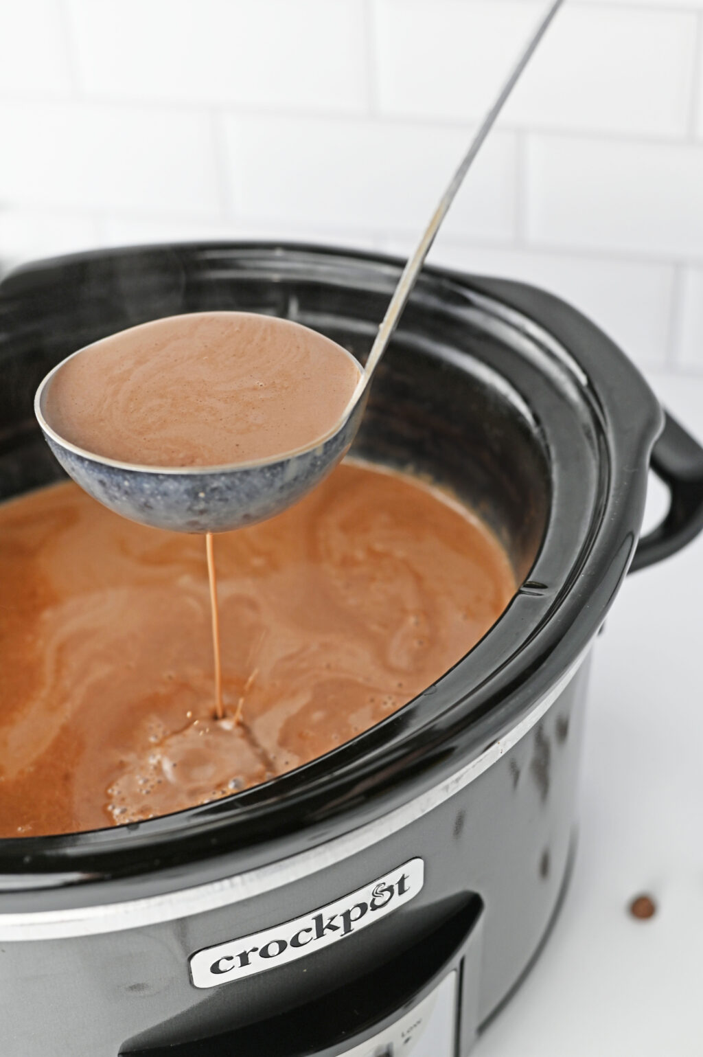 metal ladle scooping hot chocolate out of slow cooker