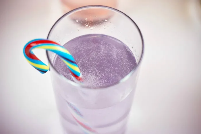 colorful candy cane melting in a glass of sprite