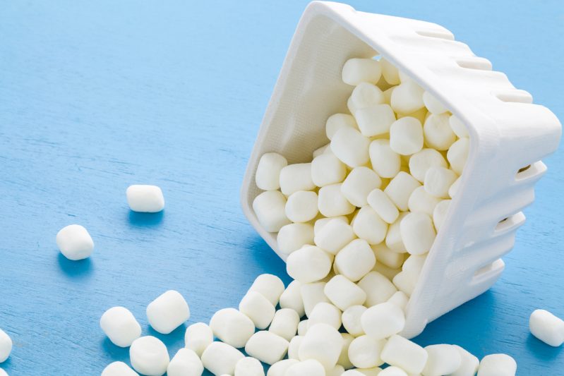 Small round white marshmallows on blue background.