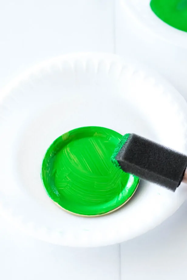 jar lids painted green on a paper plate