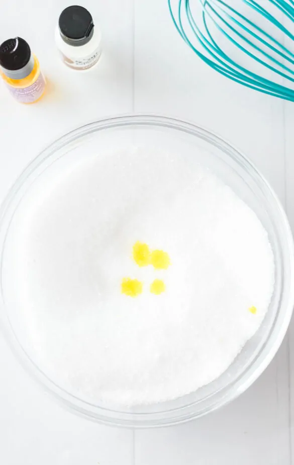 bowl of epson salt with yellow food coloring drops inside