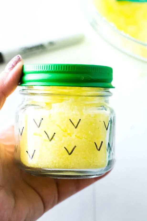 a hand holding a jar of bath salts that looks like a pineapple