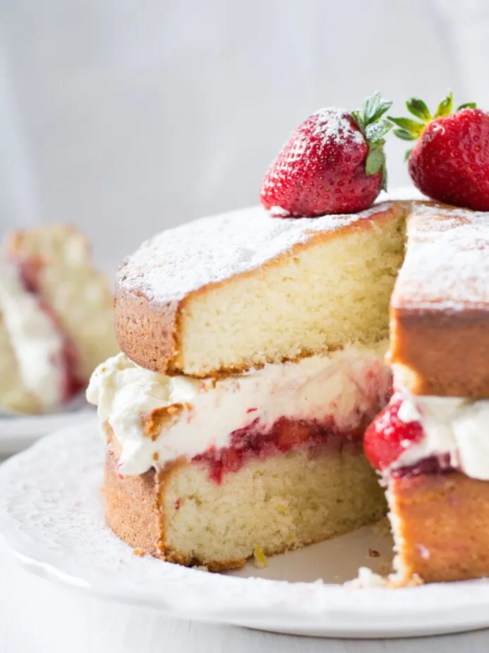 sponge cake cut open with frosting and berries