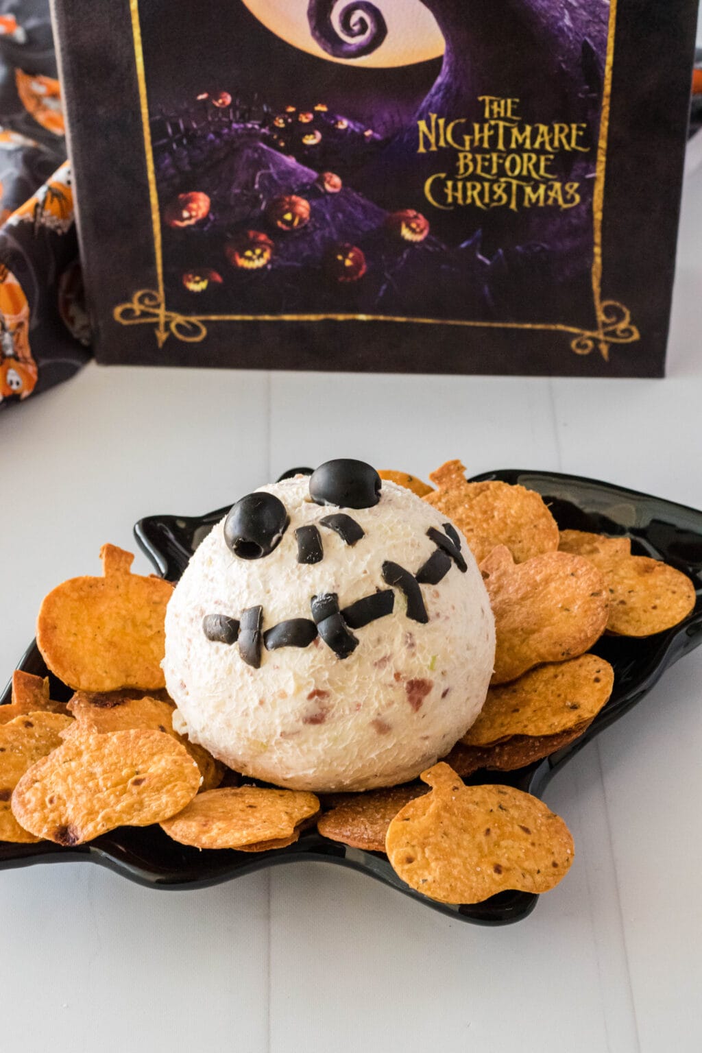 a cheese ball on a plate with pumpkin chips around it
