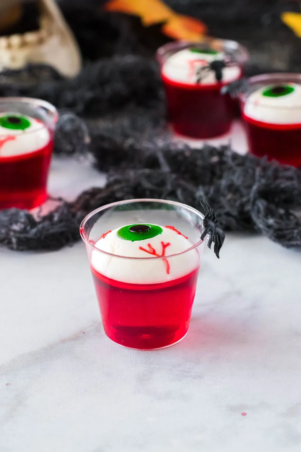 a jello shot in a cup with an eyeball gummy on top