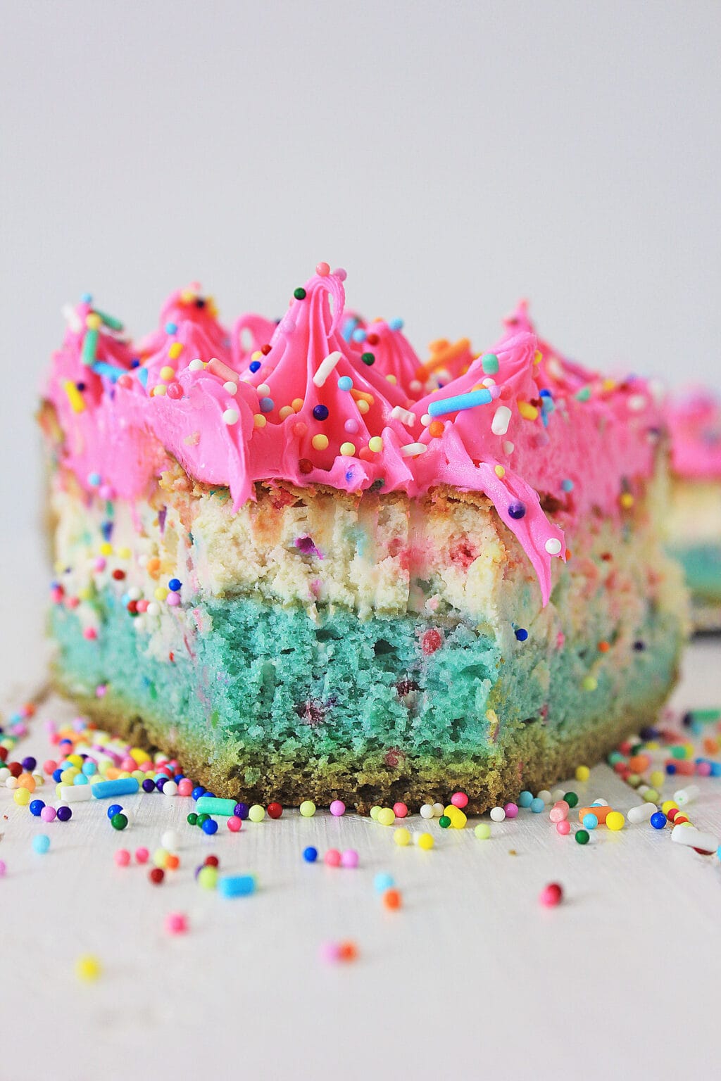 An upclose view of a piece of funfetti cheesecake with a bite taken out of it.