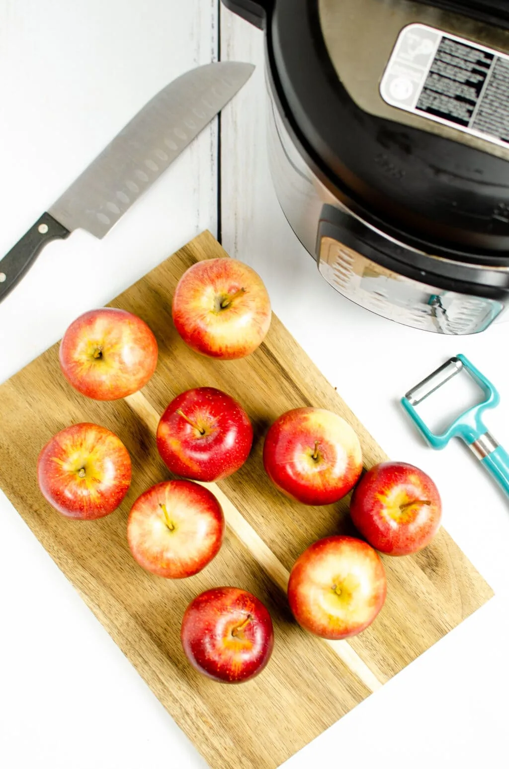 apples on a cutting board with an instant pot in the back