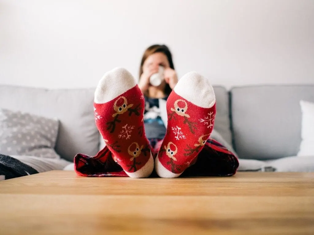 mom relaxing on couch wearing Christmas socks and drinking coffee
