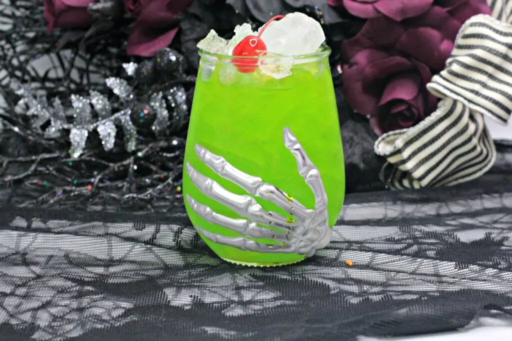 horizontal photo of green hocus pocus cocktail in a Halloween glass