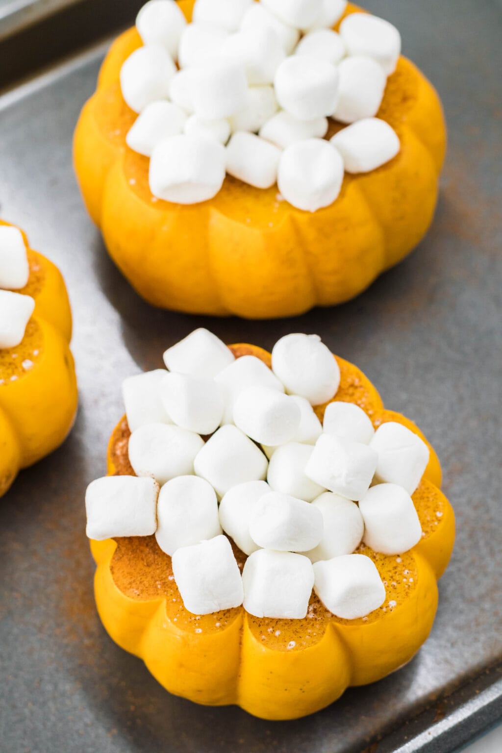 mini pumpkins on a baking sheet covered in marshmallows 