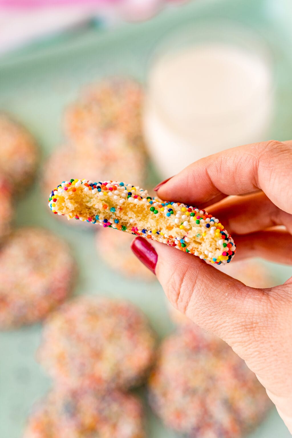 woman's hand holding funfetti cake mix cookie with bite taken out of it