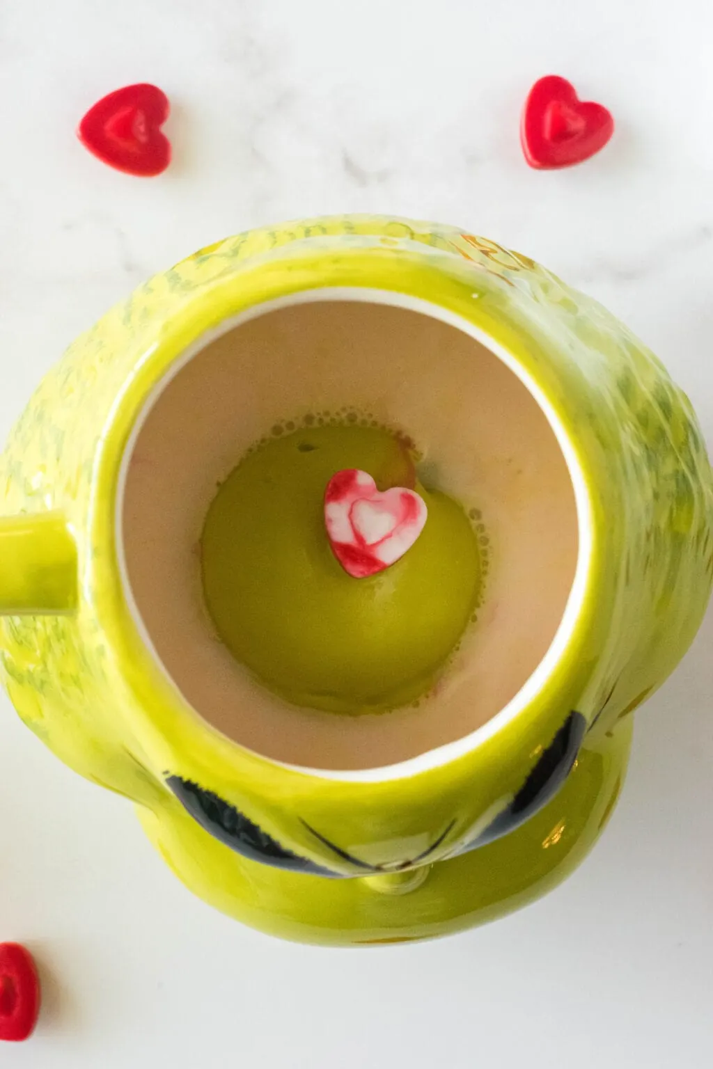 grinch hot cocoa bomb being melted into a grinch mug with hot milk