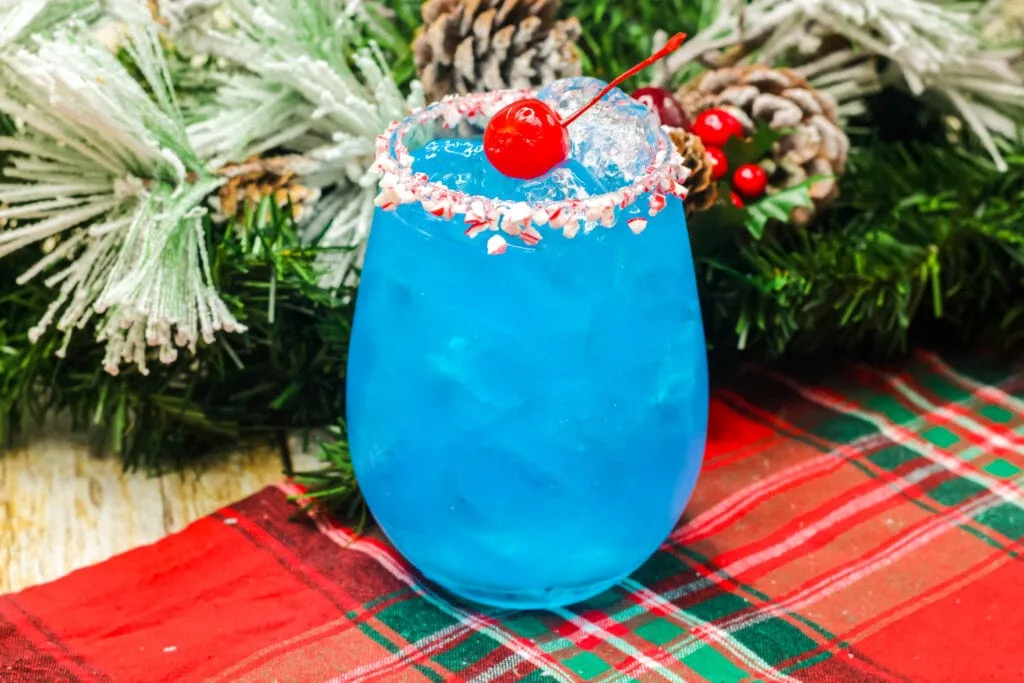 blue cocktail in a glass with red cherry on top