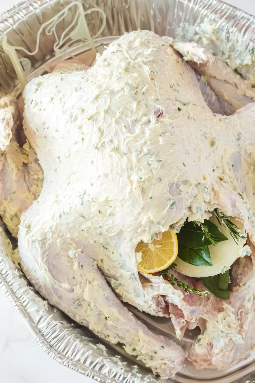 raw turkey covered in garlic herb butter