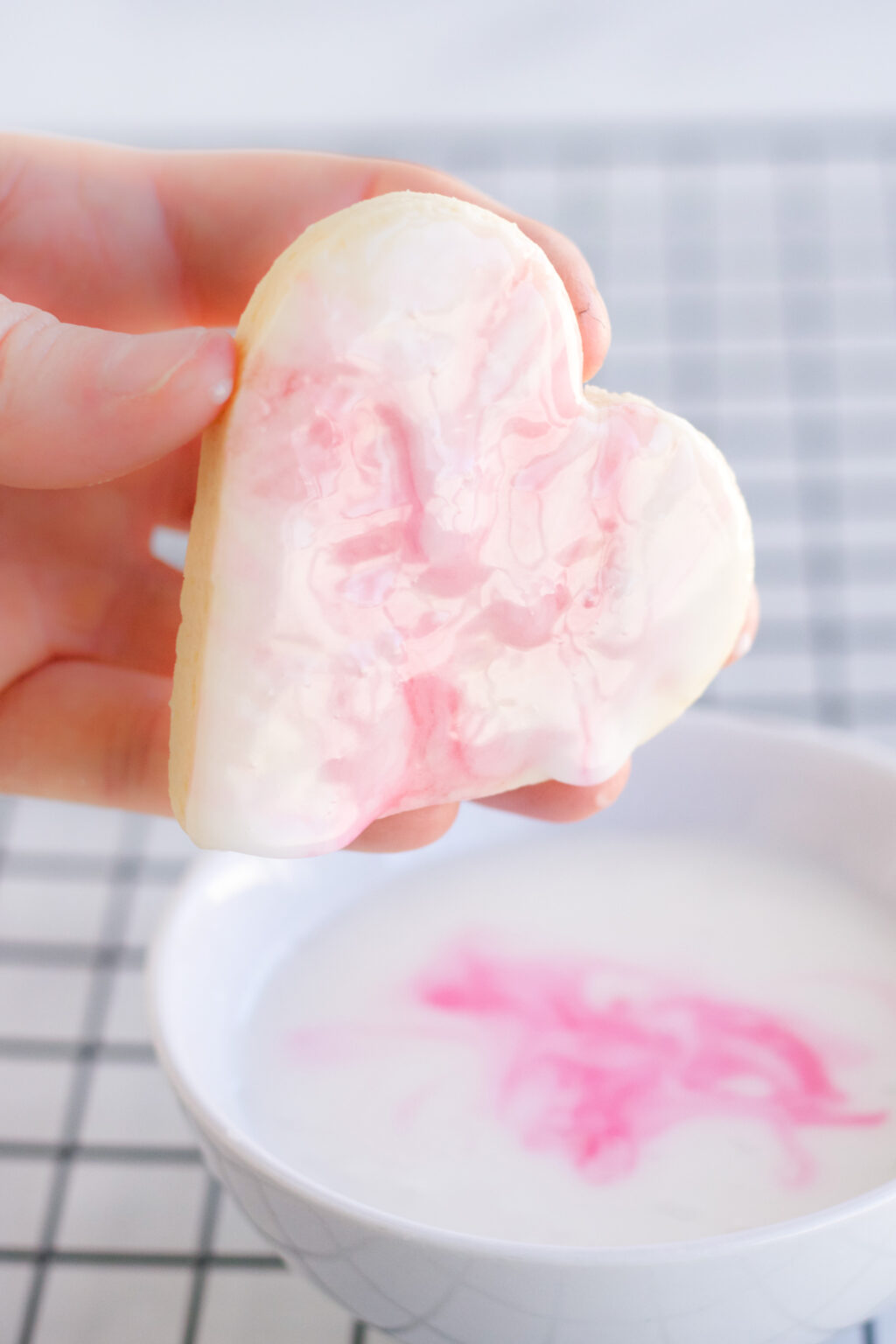 heart cookie being dipped into marbled icing