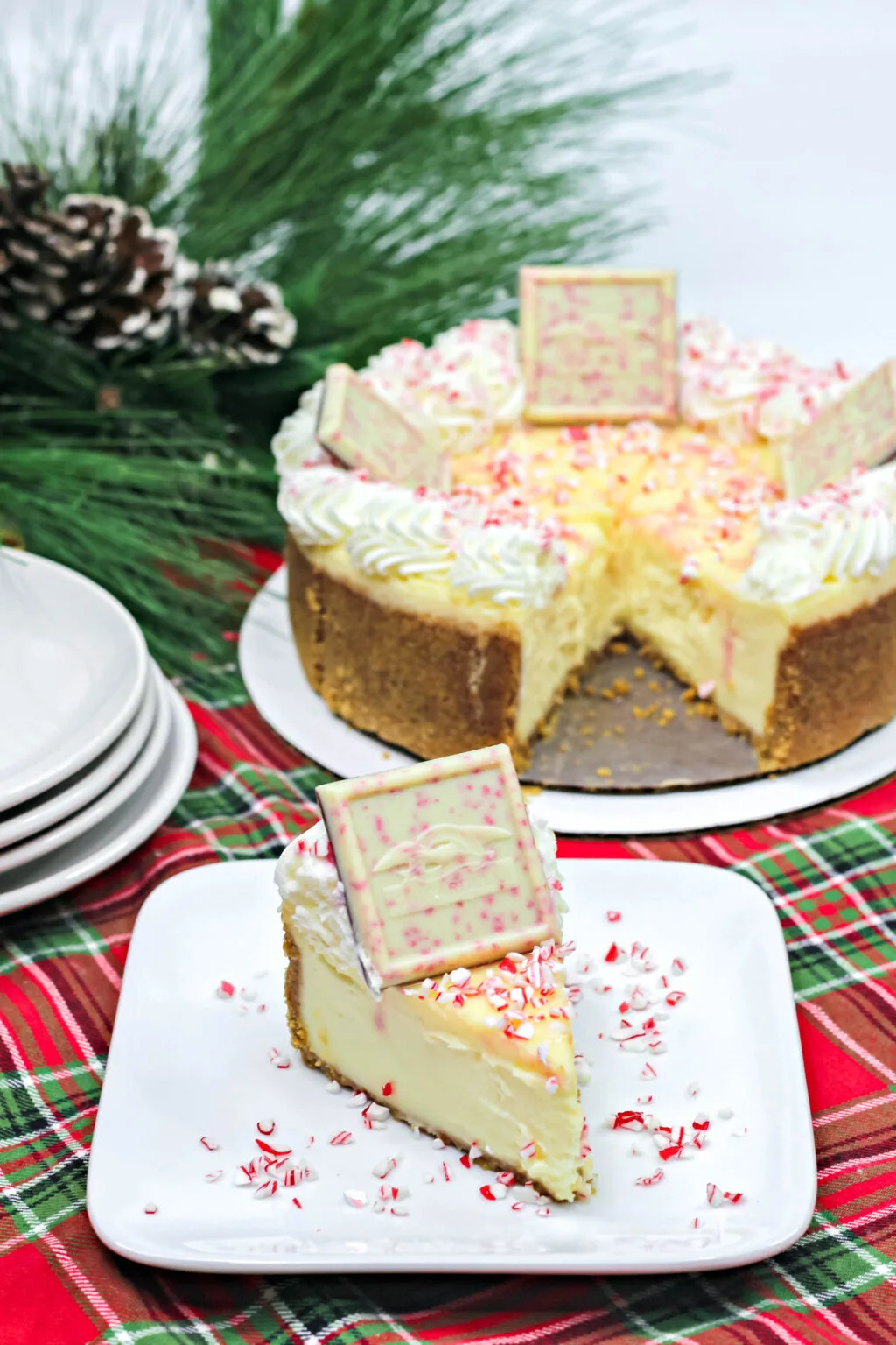 large peppermint cheesecake on a pan beside a slice of white chocolate peppermint cheesecake