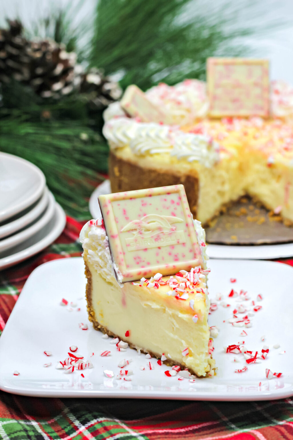 A slice of Ghirardelli White Chocolate Peppermint Cheesecake on a white place