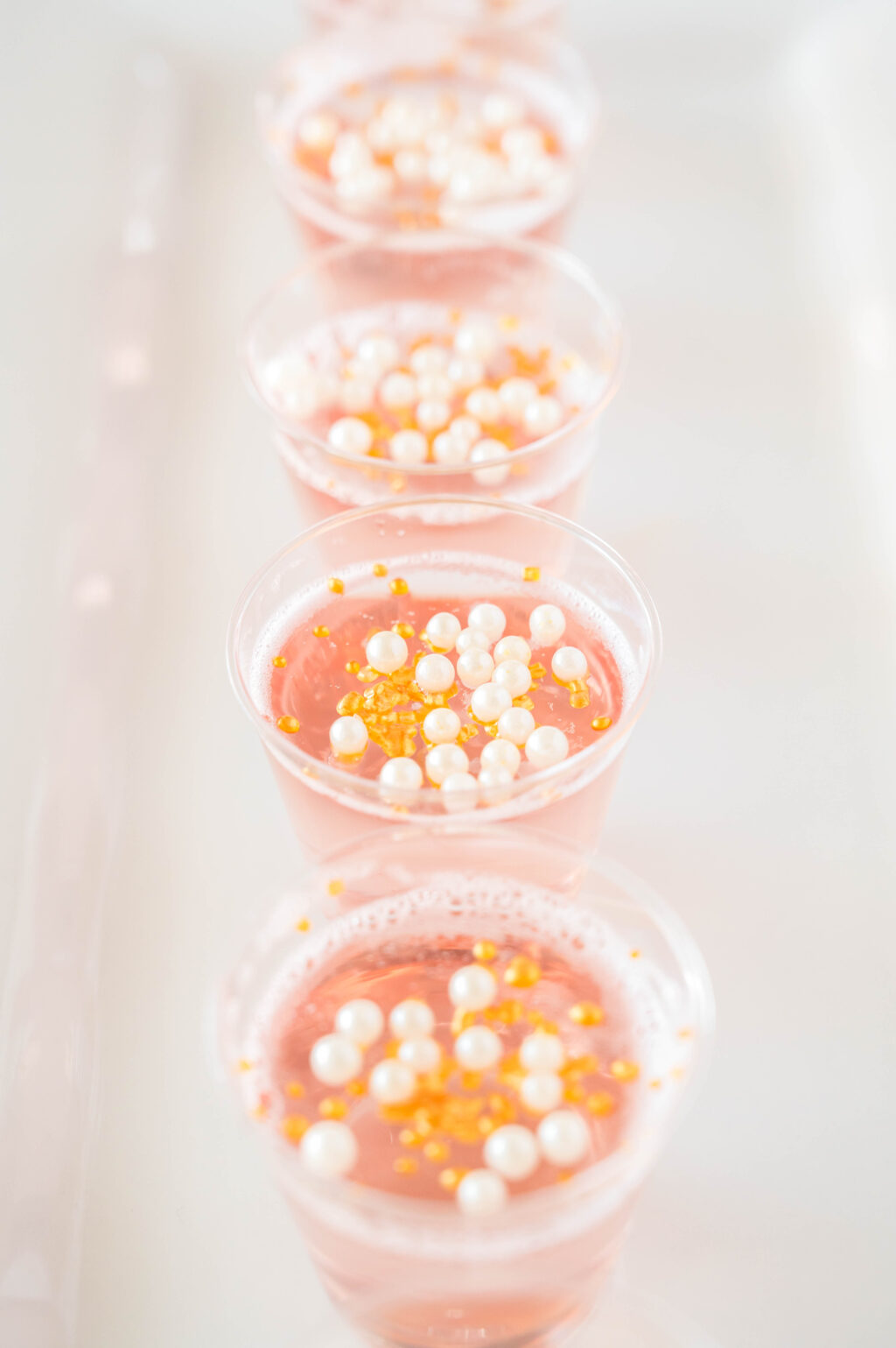 pink champagne jello shots lined up on a plate