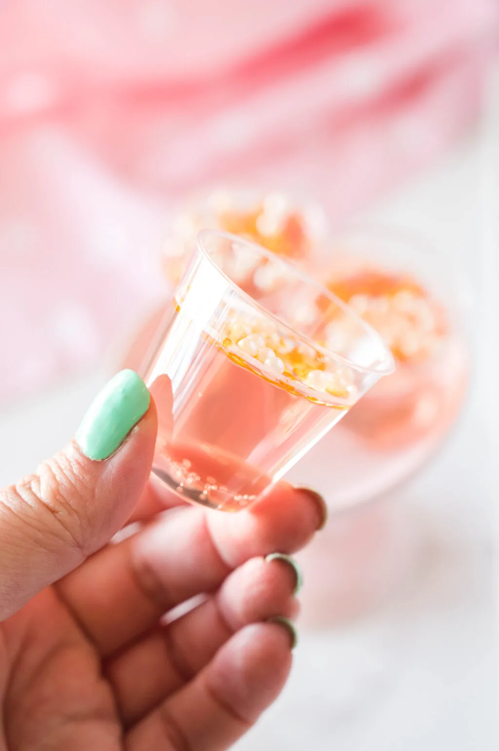 side view of hand holding a pink champagne jello shot