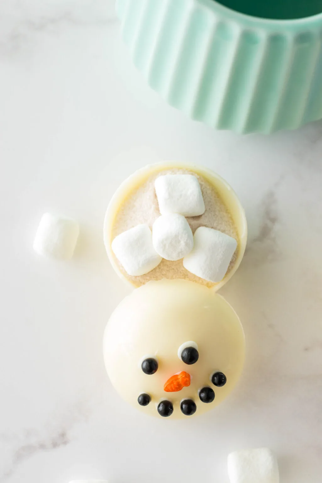 open snowman hot chocolate bomb near mug