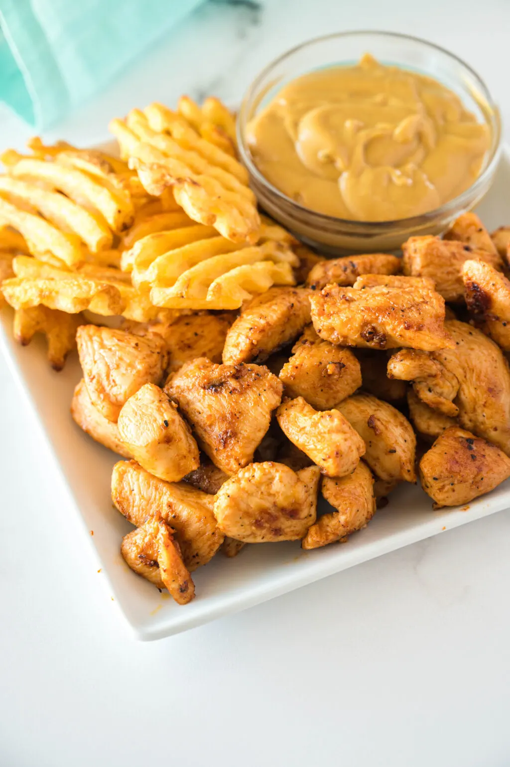 copycat chick-fil-a grilled nuggets on a plate with waffle fries and chick fil a sauce