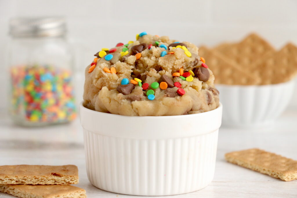 cup of edible chocolate chip cookie dough with rainbow sprinkles on top