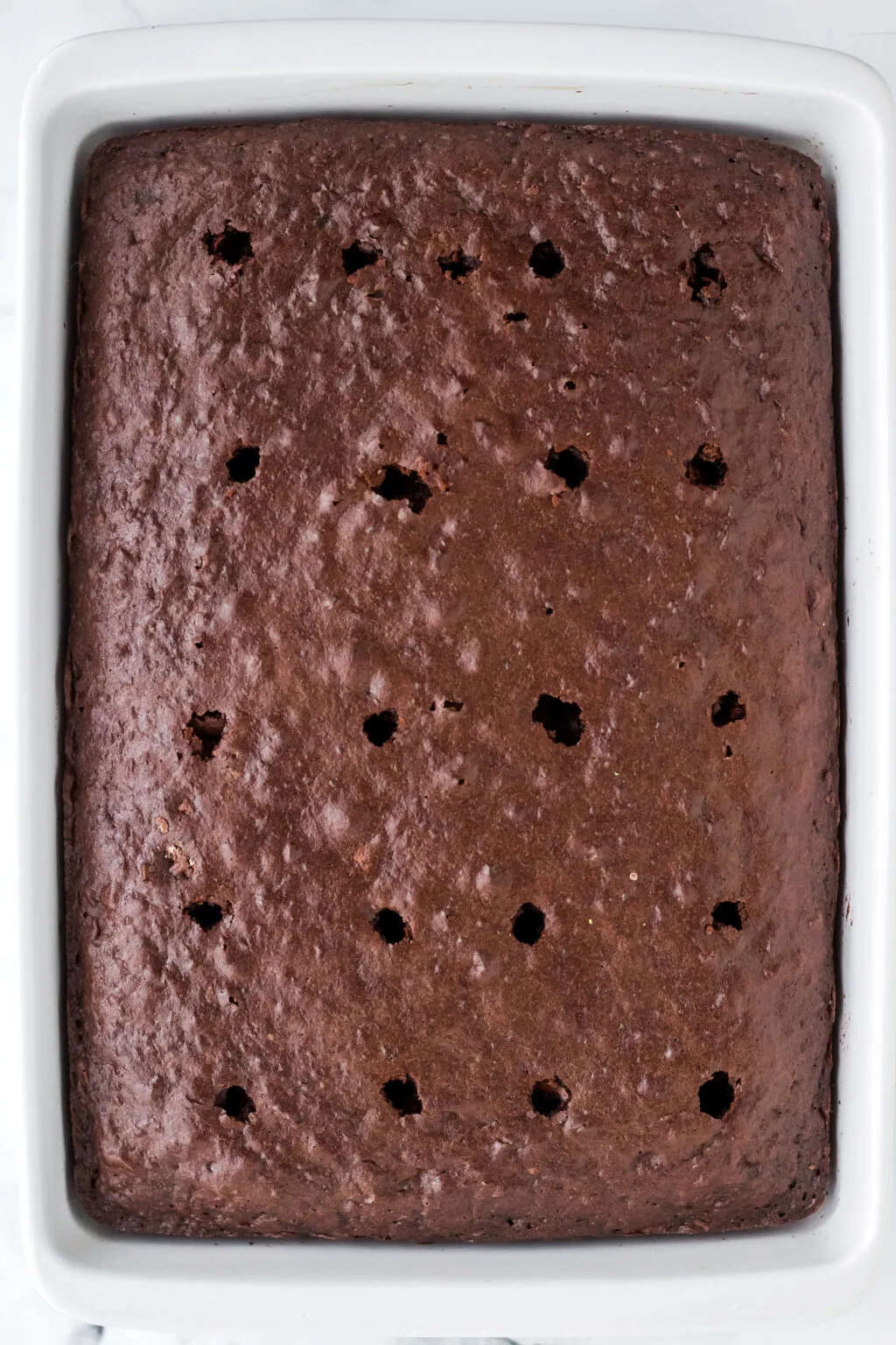 holes poked into chocolate cake for oreo poke cake filling