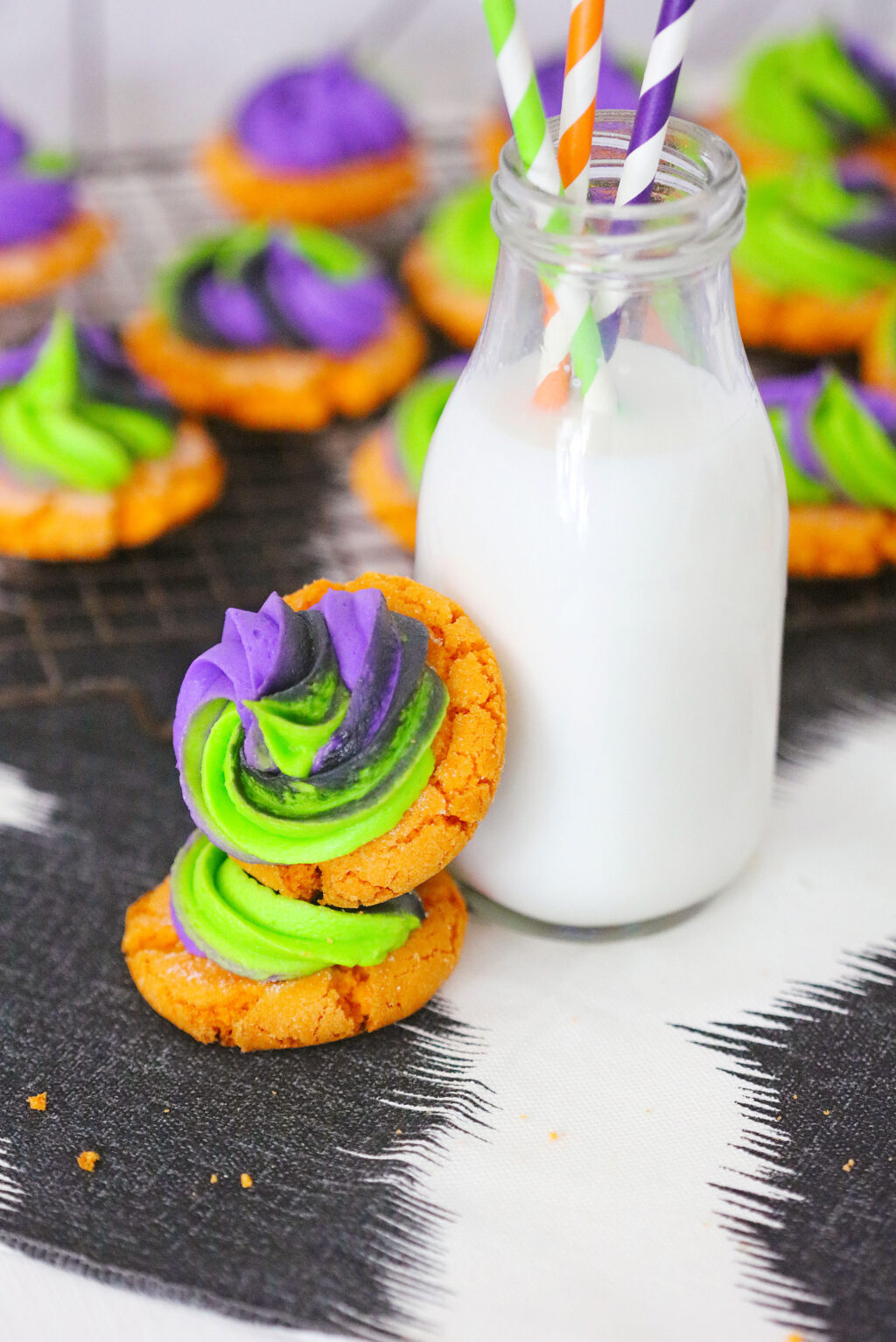 Pumpkin Sugar Cookies With Buttercream Swirl Frosting stacked against a glass of milk