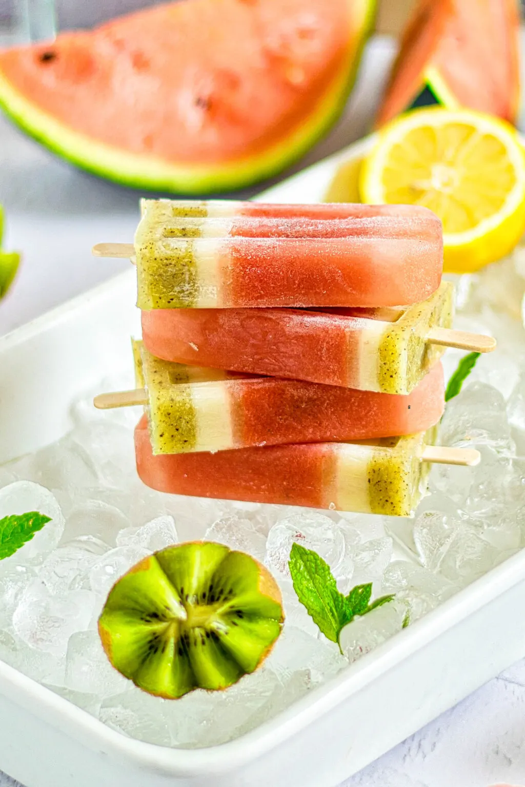 stacked homemade watermelon popsicles on tray of ice