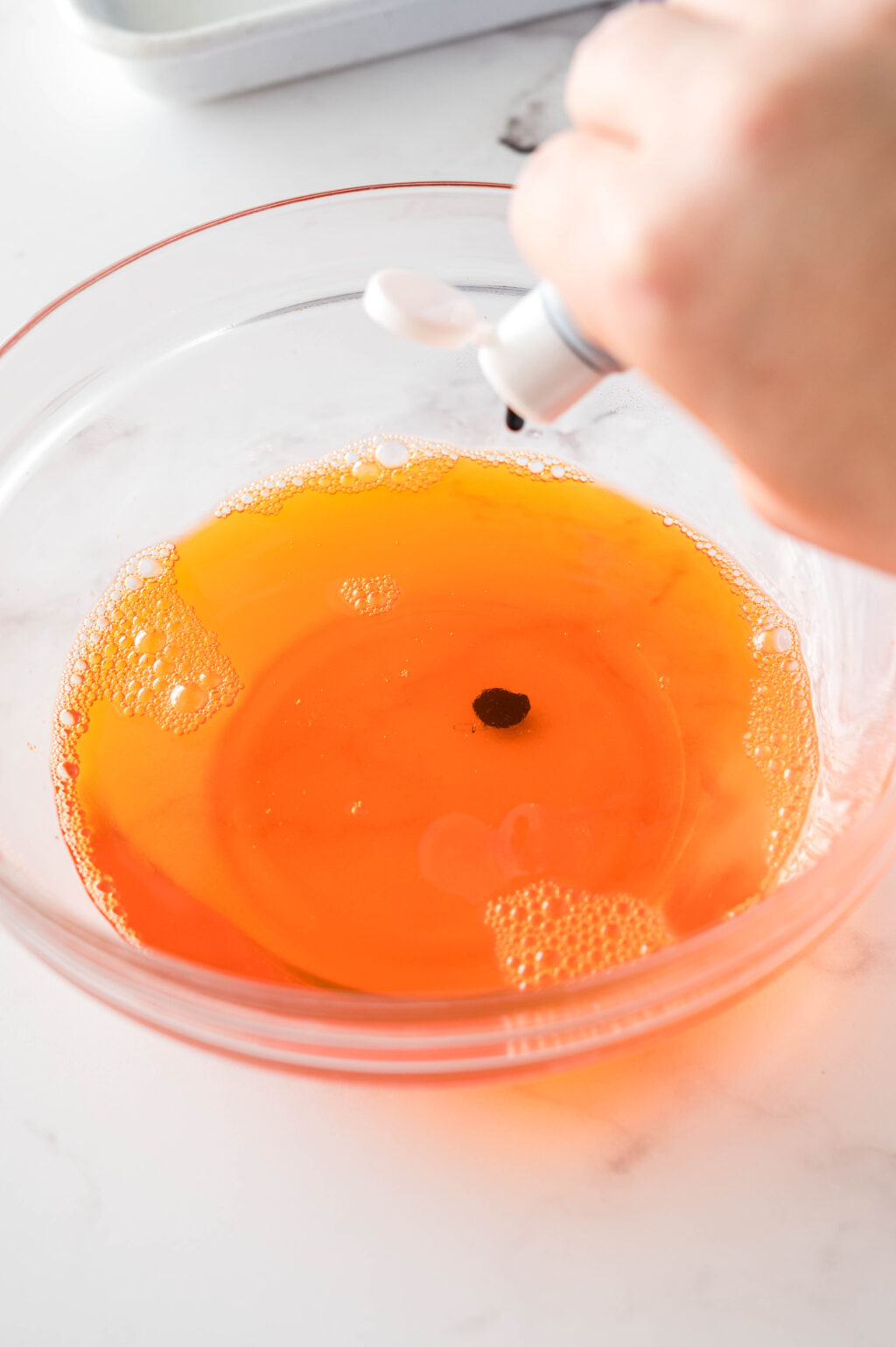 black food color being put into orange jello mixture
