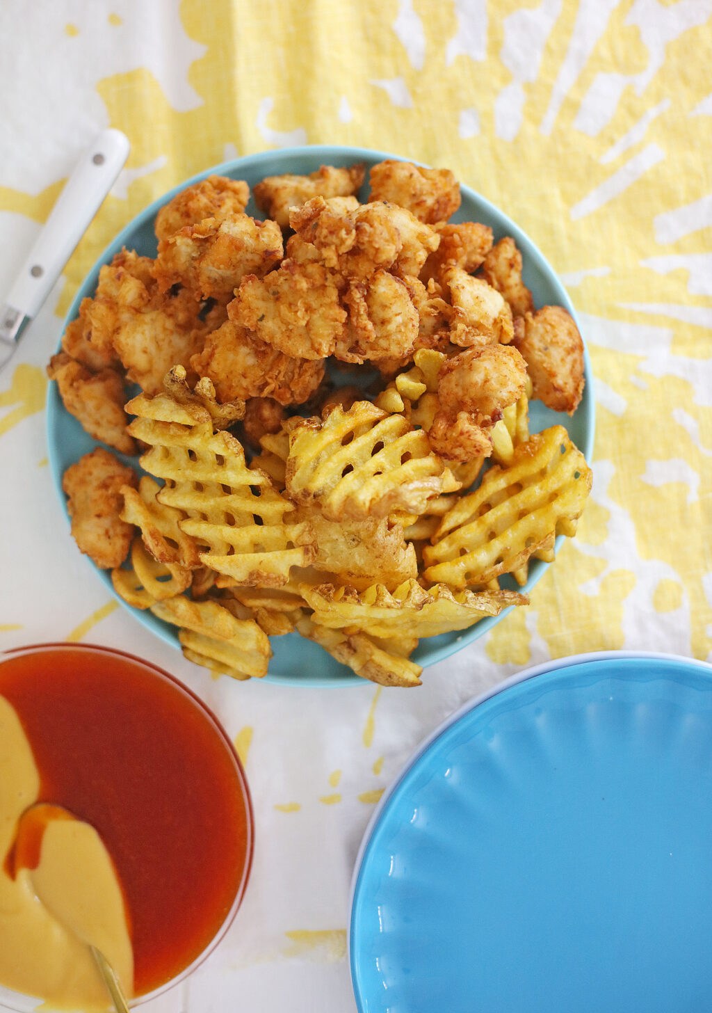 homemade chick-fil-a nuggets on a blue plate with a side of waffle fries
