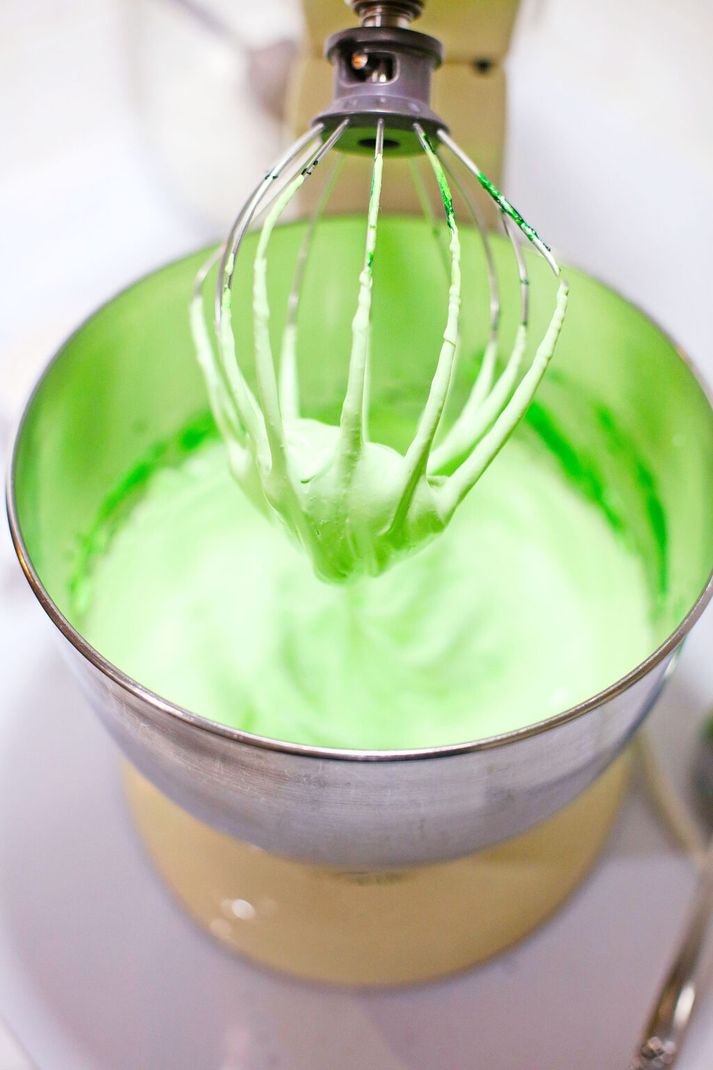 bright green meringue cookie mix inside a stand mixer