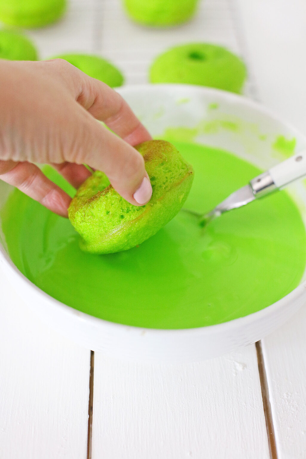 grinch donut being dipped into green frosting