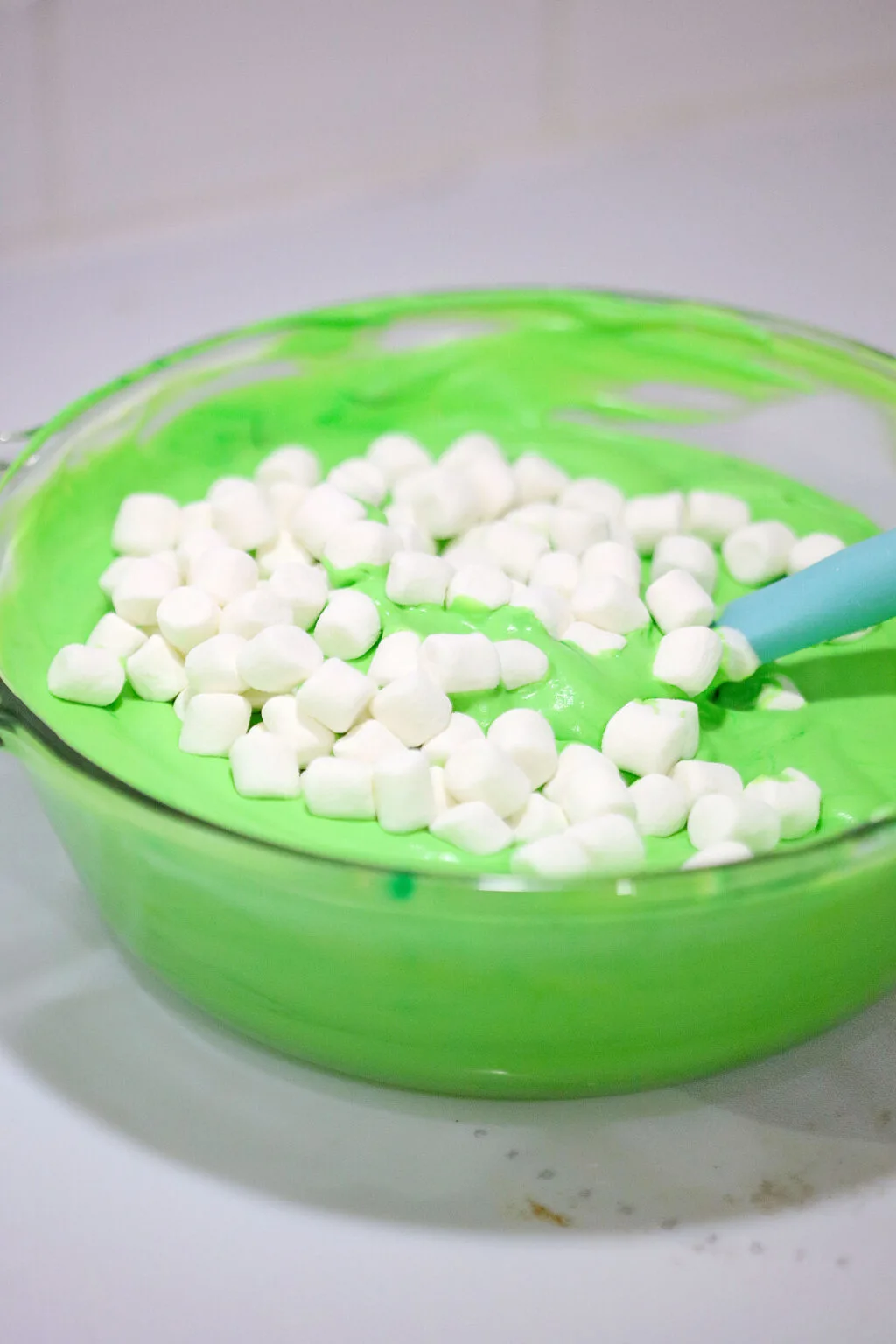 green whipped cream in a glass bowl topped with mini marshmallows