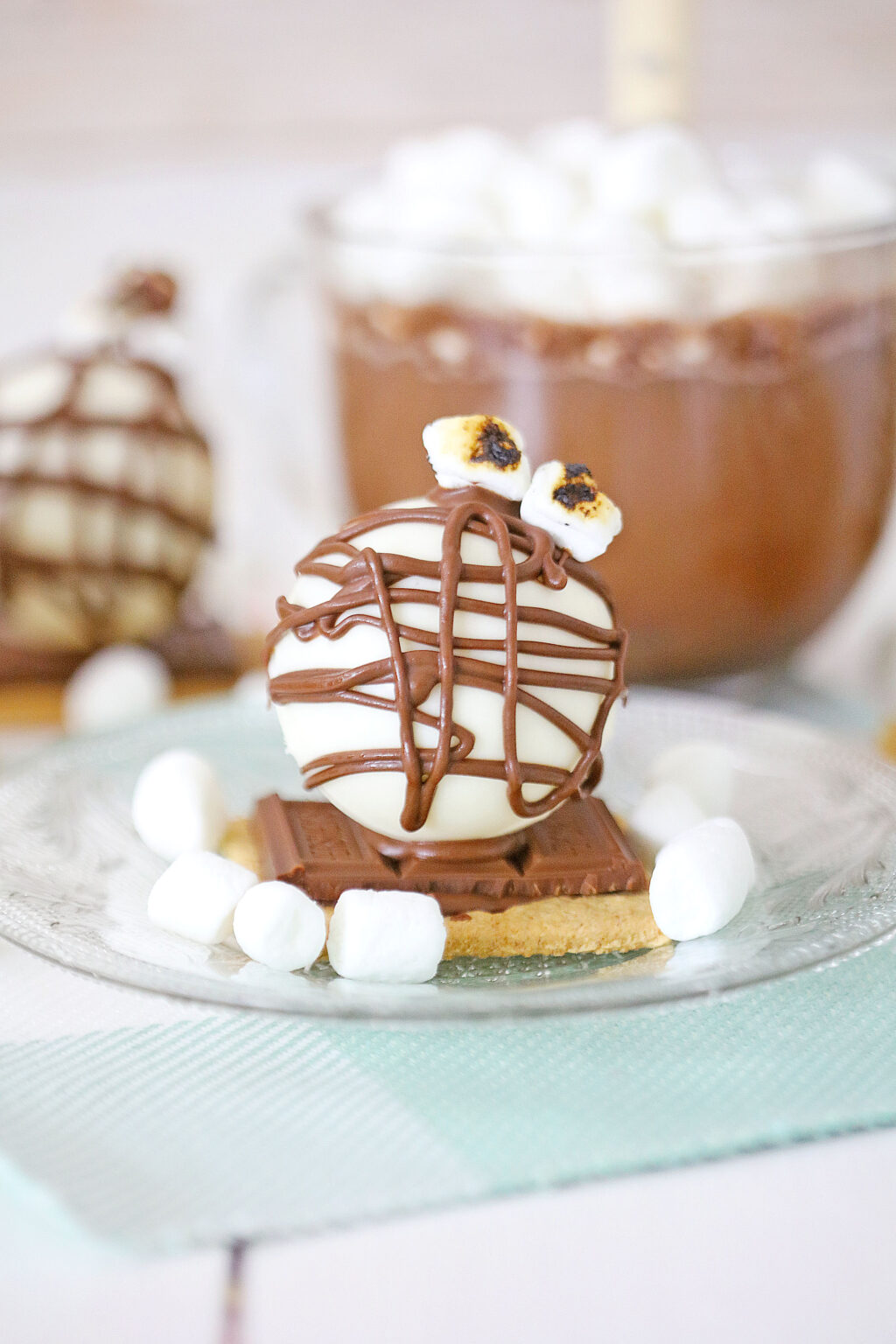 a s'mores hot cocoa bomb on a clear glass plate