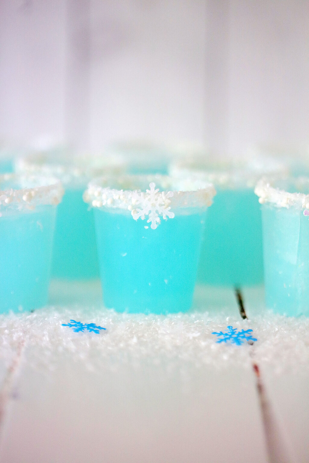 bright blue jack frost jello shots arranged on a white wood table
