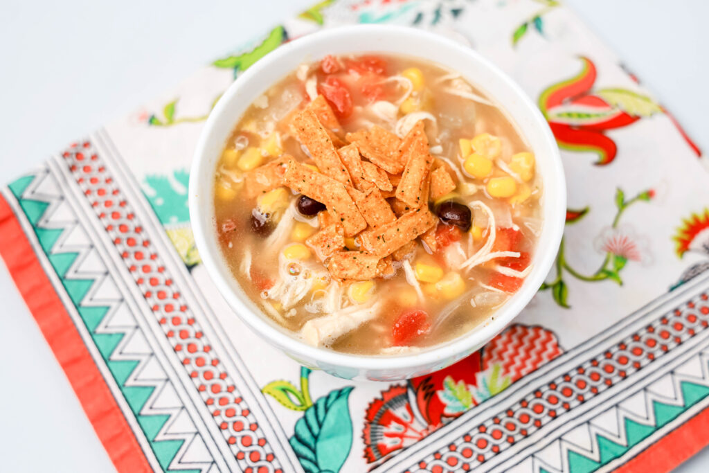 a white bowl of chick-fil-a chicken tortilla soup on a colorful napkin