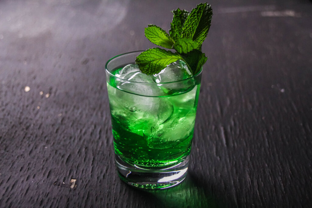 green irish cocktail in a glass with ice and fresh mint