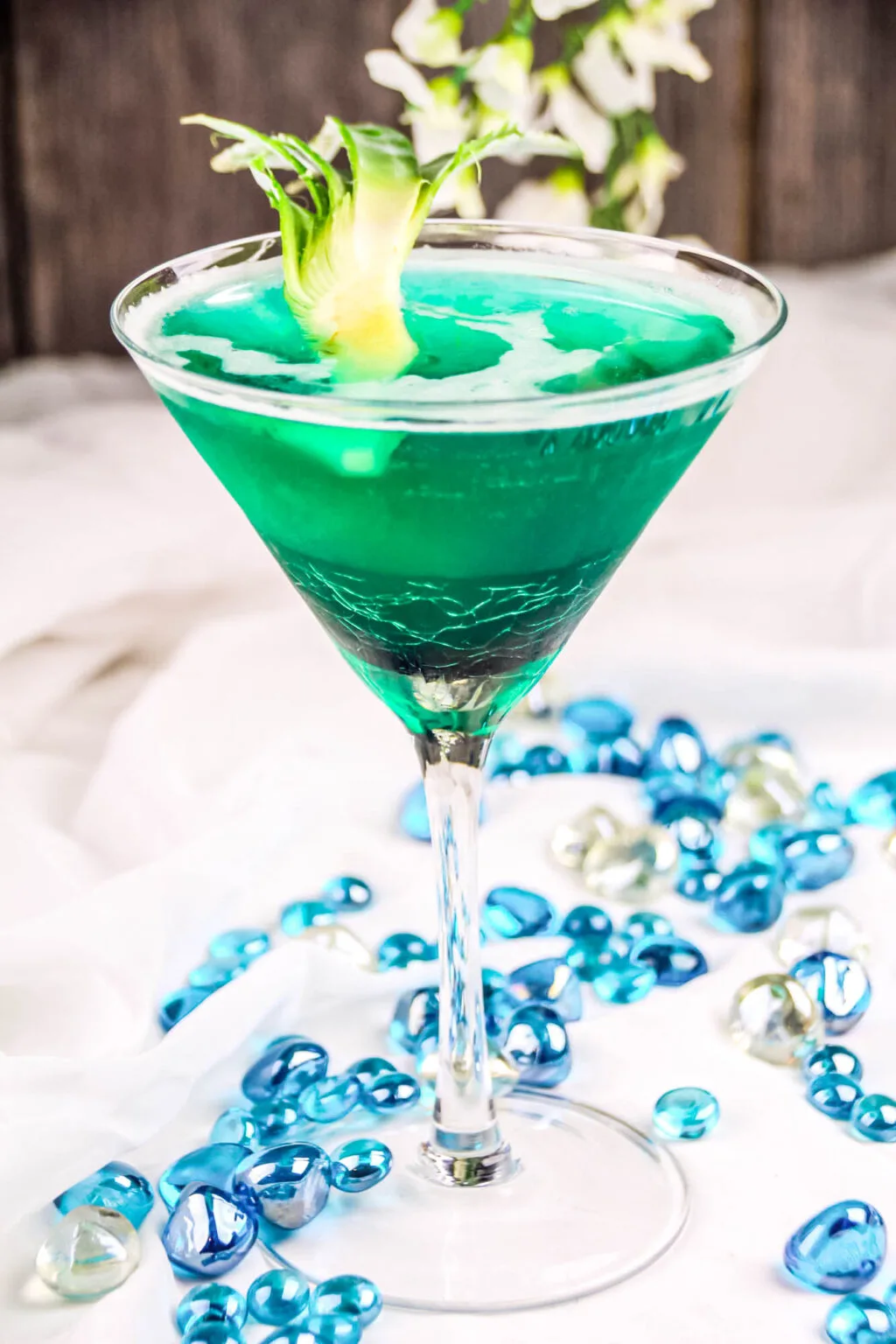 side view of bright blue ocean drink in a martini glass