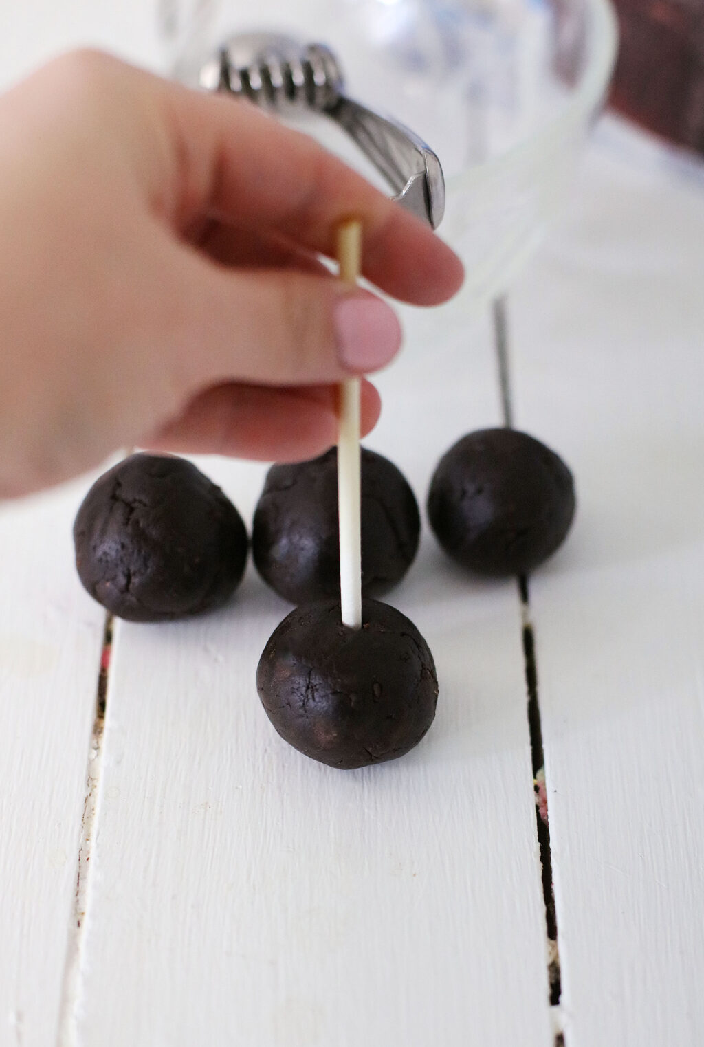 candy stick being inserted into chocolate cake ball