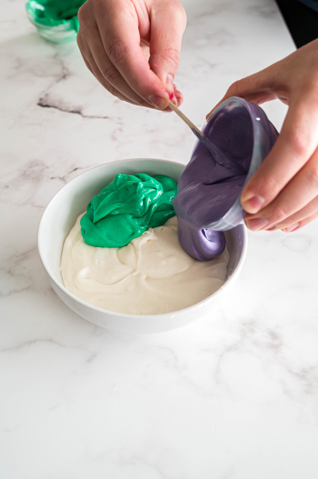 hand pouring purple dip into large bowl