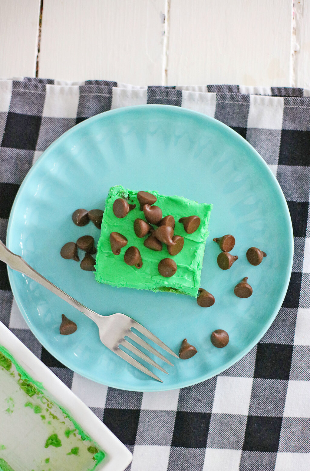 top view of a mint chocolate chip cookie bar on a blue plate with a fork