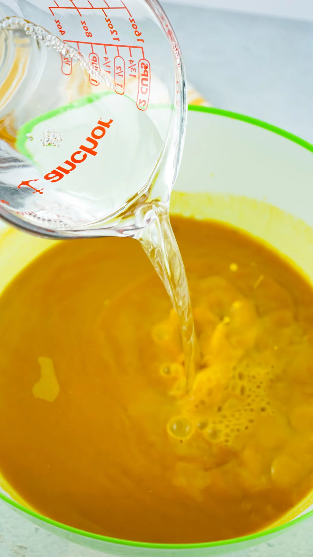vinegar being poured into pan of turmeric water