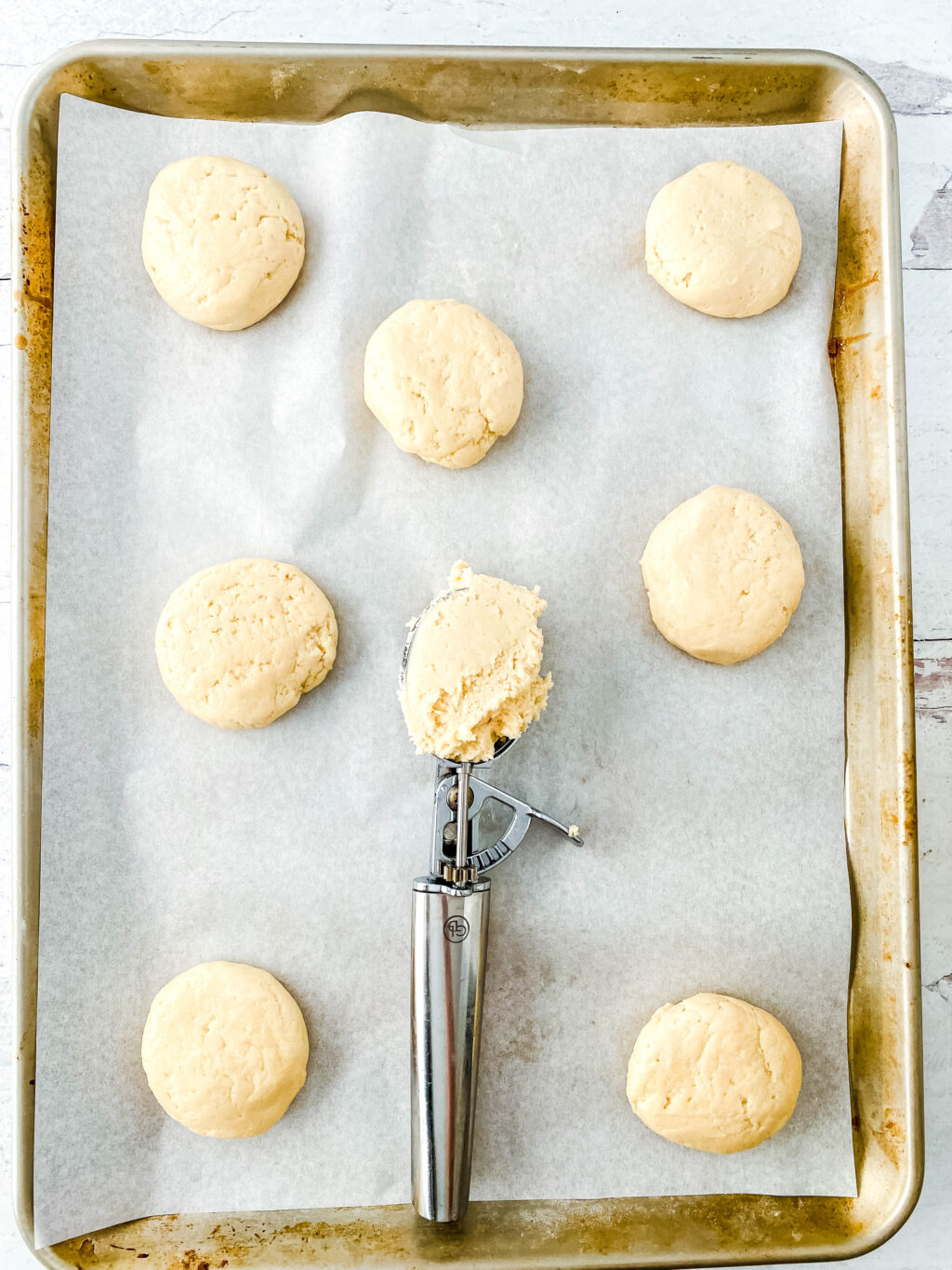 cookie scoop putting sugar cookie dough on baking sheet