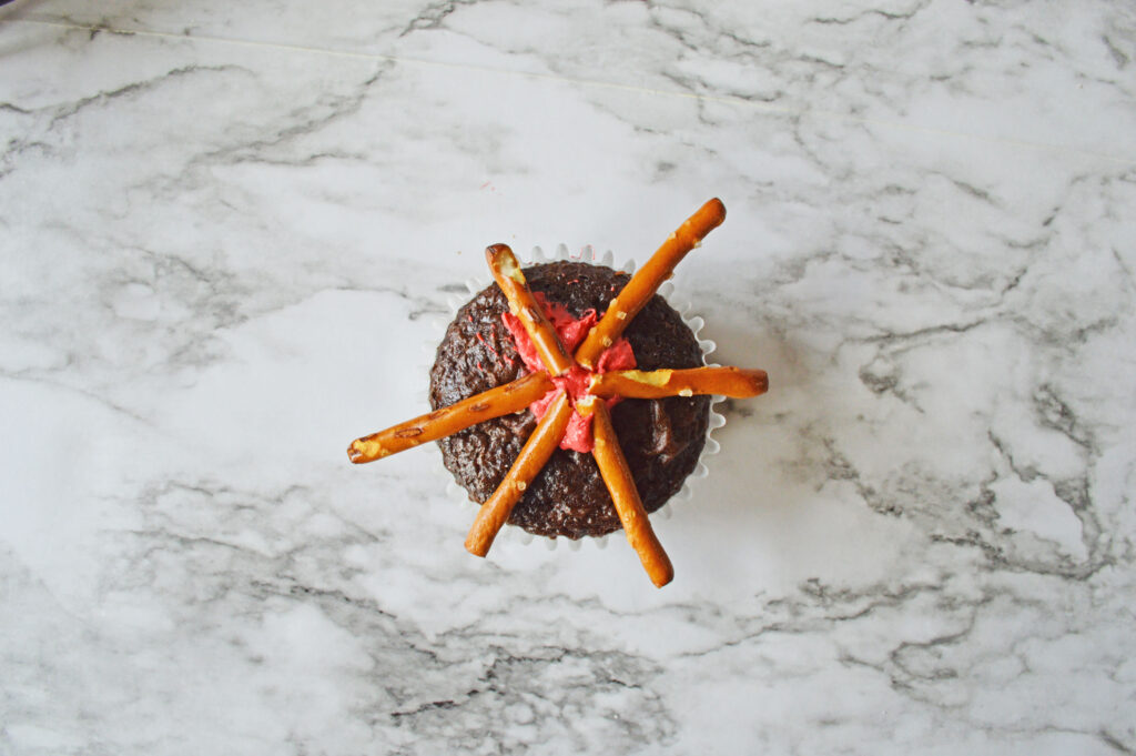 decorating a chocolate cupcake with pretzel sticks