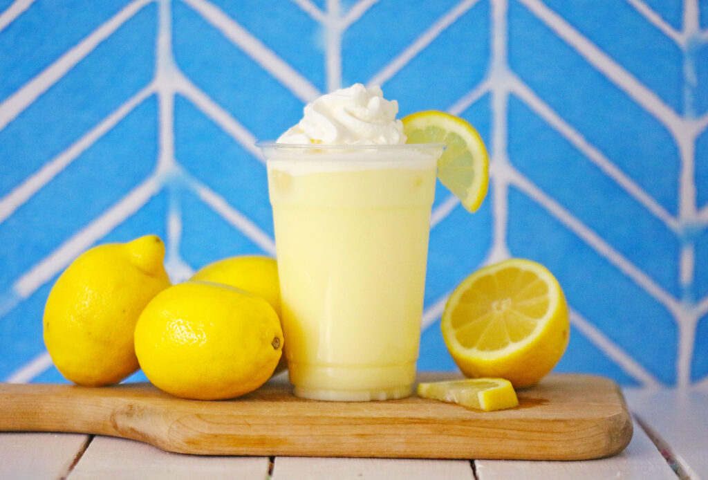 copycat chick-fil-a frosted lemonade in a clear cup with whipped cream and a lemon on top