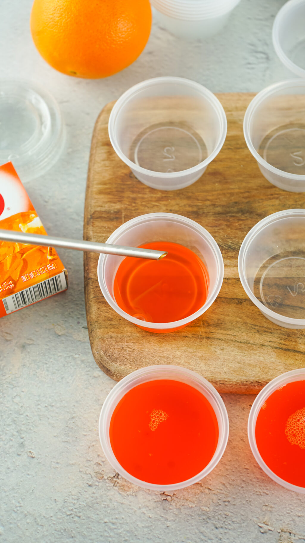 injector filling plastic shot glass cups with jello shot mixture