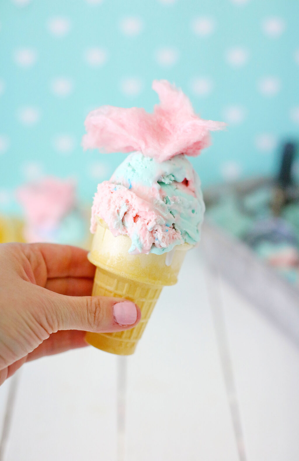 hand holding homemade cotton candy ice cream in a cone