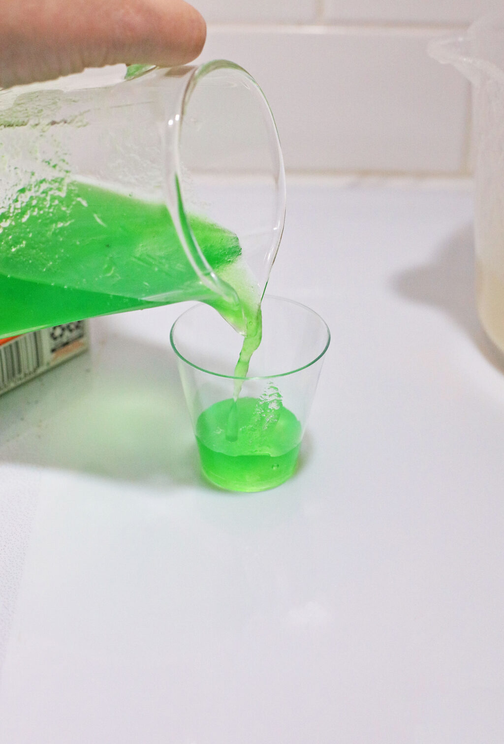 green gelatin mixture pouring into shot glass